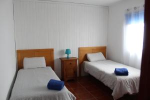 Dos camas en una habitación con almohadas azules. en Capellania en Tijarafe