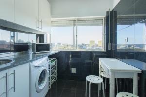uma cozinha com uma máquina de lavar roupa e um lavatório em Vista Rio em Lisboa