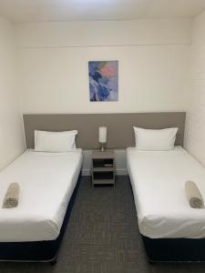 a hotel room with two beds and two nightstands at Adina Place Motel Apartments in Launceston