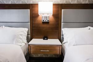 a room with two beds and a nightstand between them at Holiday Inn Hotel & Suites Calgary South - Conference Ctr, an IHG Hotel in Calgary