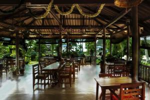 an empty restaurant with wooden tables and chairs at Dewshore Resort in Ban Tai