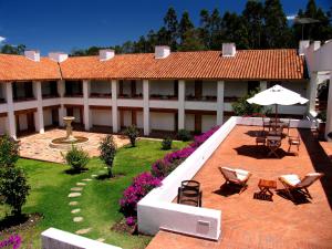 a building with a courtyard with chairs and an umbrella at Hotel Casa de los Fundadores in Villa de Leyva