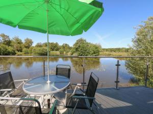 a table and chairs on a dock with an umbrella at Lakeside Lodge in East Harling