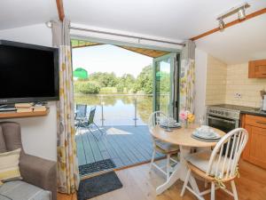 a kitchen and dining room with a table and a television at Lakeside Lodge in East Harling