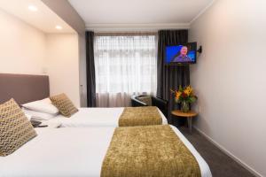 a hotel room with two beds and a tv at Quest on Johnston Serviced Apartments in Wellington