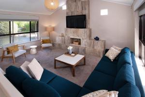 a living room with a blue couch and a fireplace at GIFFORD HOUSE in Dunsborough