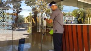 een man die voor een winkelraam staat en aan een glazen raam werkt bij KAWANA HOTEL in Kampungdurian