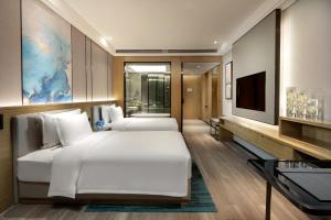 長沙市にあるWyndham Changsha Southのベッド2台とテレビが備わるホテルルームです。