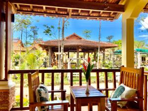 a porch with two chairs and a table with a vase on it at Villa Lien Tho in Phú Quốc