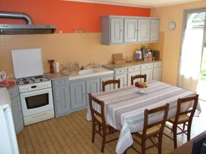 a kitchen with a table with chairs and a sink at Le Saule Argenté in La Villeneuve-au-Châtelot