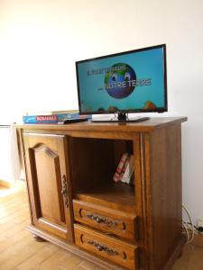 a tv on top of a wooden entertainment center at Le Saule Argenté in La Villeneuve-au-Châtelot