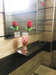 un vaso di vetro su uno scaffale con due rose di Shiny Villa a Nuwara Eliya