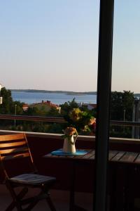 a table and a chair on a balcony with a view of the water at Apartments Roža in Medulin