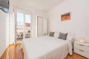 a white bedroom with a bed and a balcony at Enna house with private jacuzzi in Novalja
