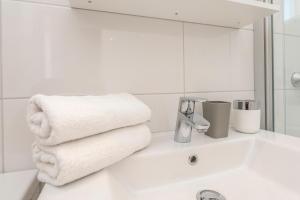a white bathroom with towels on a sink at Enna house with private jacuzzi in Novalja +37 photos