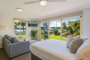 a bedroom with a bed and a couch and a window at Lakeside Holiday Apartments Merimbula in Merimbula