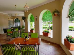 restauracja z zielonymi krzesłami, stołami i oknami w obiekcie Hotel Sonnenhof w Suczawie