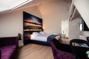 1 dormitorio con cama y sofá púrpura en Boetiekhotel Burgemeesterhuys, en Beringen