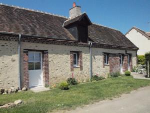 una vieja casa de piedra con una puerta blanca y una chimenea en Gîtes les Terriers, en Saint-Jean-Froidmentel