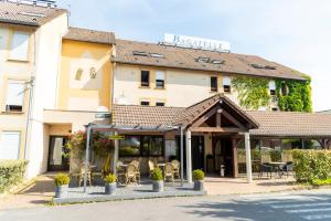 un hotel con sedie e tavoli di fronte a un edificio di Hôtel Bagatelle Paris Nord Roissy CDG a Goussainville