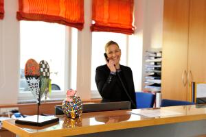 Eine Frau, die auf einem Handy in einem Büro redet. in der Unterkunft Hotel Vis à vis in Lindau