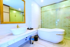 a bathroom with a tub and a sink and a mirror at Hoa Dao Hotel in Hòa Bình