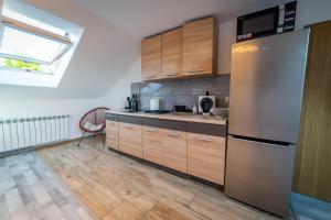 a kitchen with wooden cabinets and a stainless steel refrigerator at Apartament Nad Jeziorem Mikołajki in Mikołajki