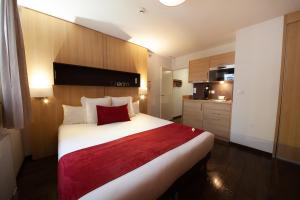 una camera da letto con un grande letto bianco con una coperta rossa di Apparthotel Privilodges Carré de Jaude a Clermont-Ferrand