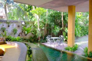 a pool with a table and chairs in a garden at The Weenee Boutique in Hat Yai