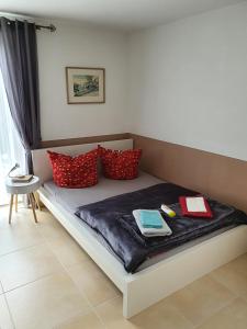 łóżko z czerwonymi i niebieskimi poduszkami w obiekcie Haus Marianne w mieście Weilheim