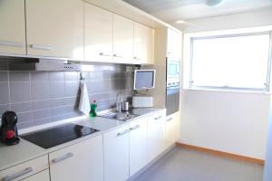 eine Küche mit weißen Schränken, einem Waschbecken und einem Fenster in der Unterkunft Sotell Apartment Gran Via Europa BCN in Las Corts