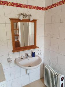 W łazience znajduje się umywalka i lustro. w obiekcie Haus Marianne w mieście Weilheim