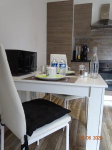 - une table de cuisine blanche avec une chaise et des bouteilles d'eau dans l'établissement Legend- Parking privé Gratuit- Terrasse privée- Wifi - Convert - Alimentec, à Bourg-en-Bresse