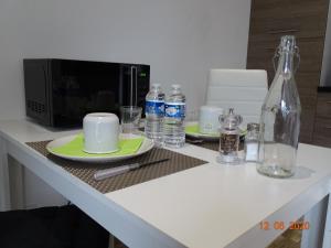 um balcão de cozinha com micro-ondas, pratos e garrafas em Legend- Parking privé Gratuit- Terrasse privée- Wifi - Convert - Alimentec em Bourg-en-Bresse