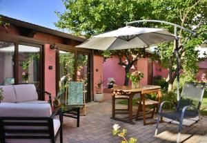 un patio con sombrilla, mesa y sillas en Flowery Inn Villa, en Alghero