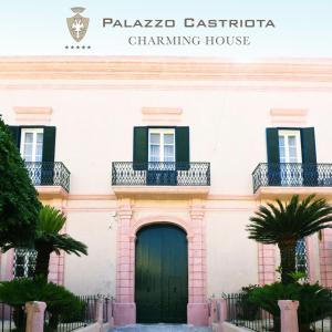 un bâtiment rose avec une porte verte et des balcons dans l'établissement Palazzo Castriota, à Alezio