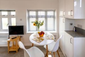a kitchen with a white table and white chairs at The Bakehouse in Worthing