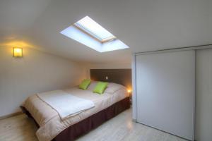 1 dormitorio con 1 cama con almohadas verdes y tragaluz en Chez Pierre à Porto-Vecchio, en Porto Vecchio