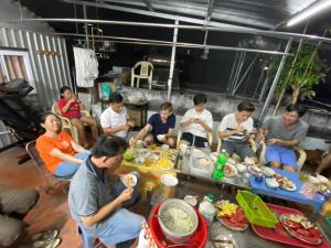 Un groupe de personnes assises autour d'une table et mangeant de la nourriture dans l'établissement Nhat an Homestay, à Hô-Chi-Minh-Ville