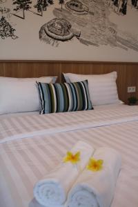 a bed with two towels and two flowers on it at Casa Living Senayan Hotel in Jakarta