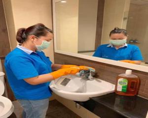 une femme lave un lavabo dans une salle de bains dans l'établissement The Bedroom Ladprao 101 Bangkok - SHA, à Bangkok