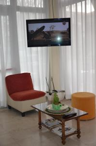 a living room with a tv and a chair and a table at Hotel Tiziana in Rimini