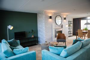 
a living room filled with furniture and a clock at Paal 8 Hotel aan Zee in West aan Zee
