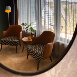 einem Spiegel mit 2 Stühlen und einem Tisch im Zimmer in der Unterkunft Paal 8 Hotel aan Zee in West aan Zee