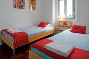 - une chambre avec 2 lits dotés de draps rouges et bleus dans l'établissement Janelas Do Tejo, à Lisbonne