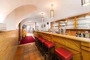 eine Bar in einem Restaurant mit roten Stühlen in der Unterkunft Hotel Heitzmann in Mittersill
