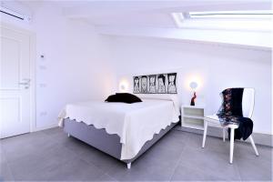 a white bedroom with a bed and a chair at Zia Pupetta Suites in Amalfi