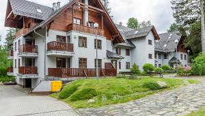 a large white building with a wooden roof at VacationClub – Okrzei 1B Apartament 19 in Karpacz