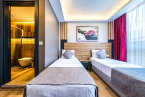 2 camas en una habitación de hotel con cortinas rosas en RUSH HOTEL İSTANBUL, en Estambul