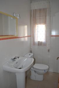 baño con lavabo y aseo y ventana en APARTAMENTO TURISTICO EL ACEBO, en Jarandilla de la Vera